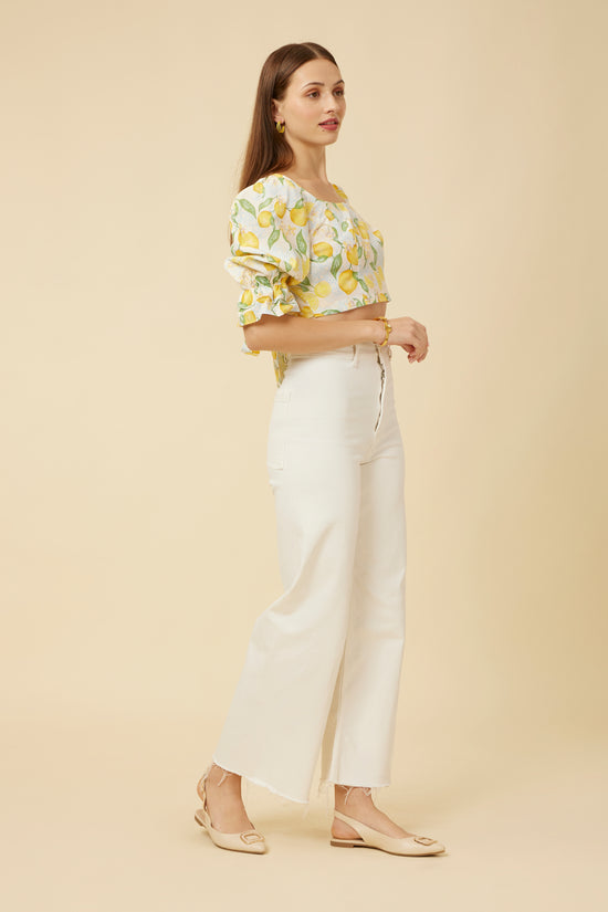 Model in Citrus Dream Crop Top turned to the side, highlighting the puff sleeves and the elegant line of the princess cut, creating a lively and flattering profile that’s perfect for a breezy summer day.