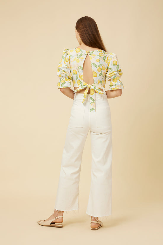 Rear view of the Citrus Dream Crop Top, detailing the stylish open back with a tie closure and the top's flattering cut, paired with white pants for a look that’s both playful and elegantly tailored.