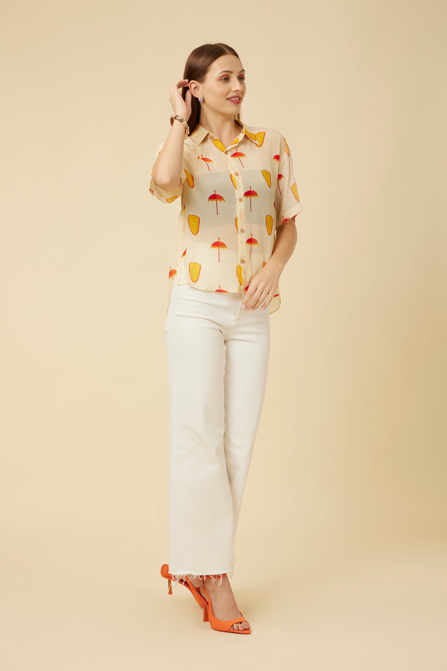 Side view of the model in the Ivory Spree Shirt featuring elbow-length sleeves and an all-over umbrella print, paired with chic white pants for a fresh look