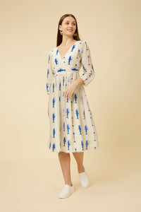 Model looking away gracefully in the Voyager Dress with a sharp V-neck and sardine print, embodying the spirit of travel in Malayalam script