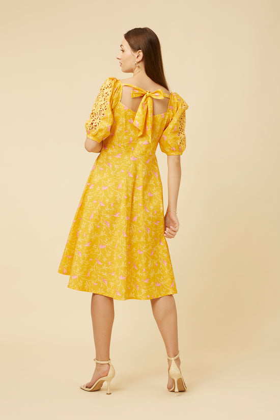 Rear view of a model wearing the Peela Sunshine Dress showing the detailed cutwork on the sleeves and the graceful yoke enhancing the dress silhouette