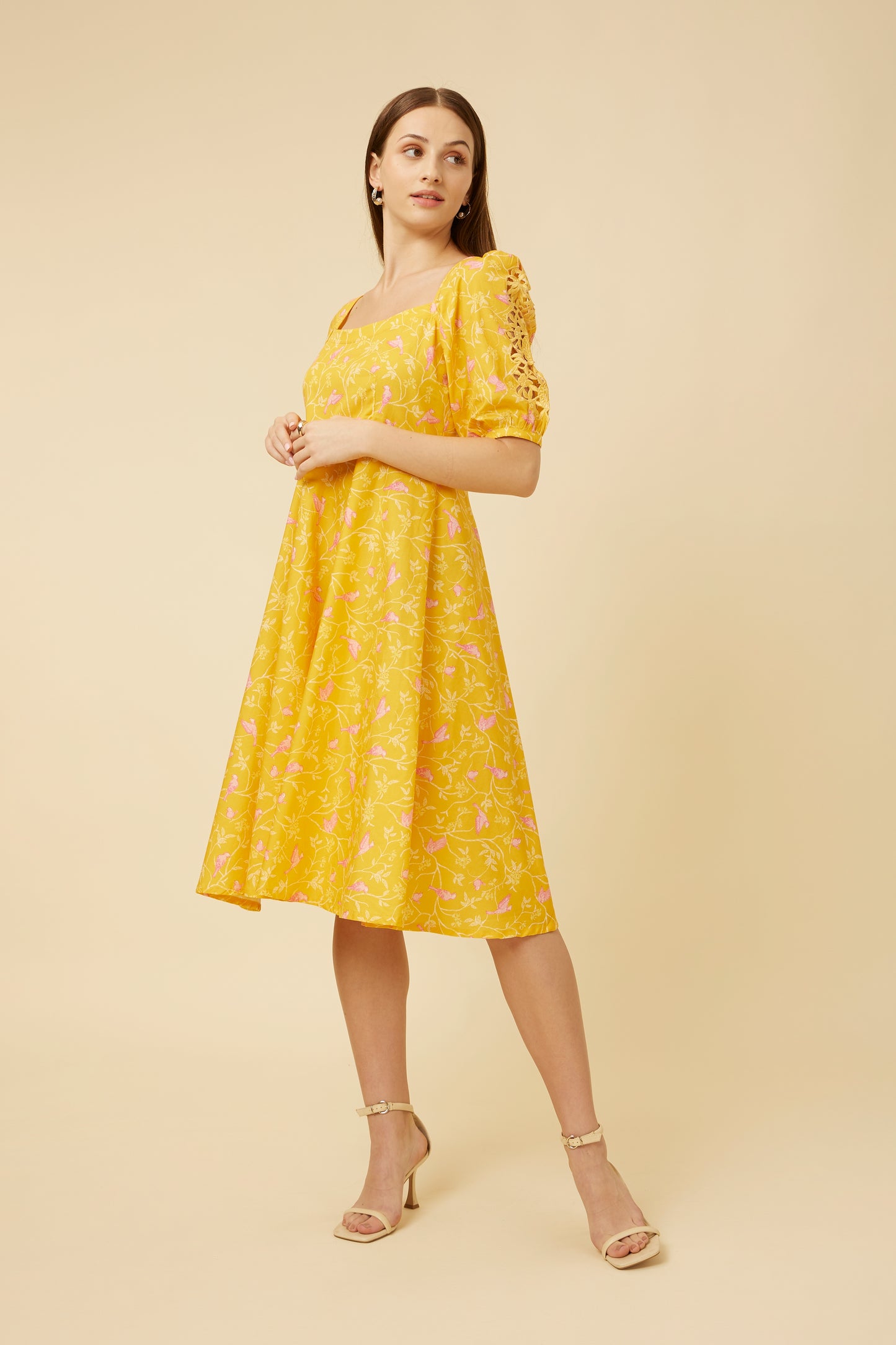  "Side profile of the ‘Peela Sunshine’ dress with delicate leaf and bird print, highlighting the modern wide neckline and umbrella cut silhouette